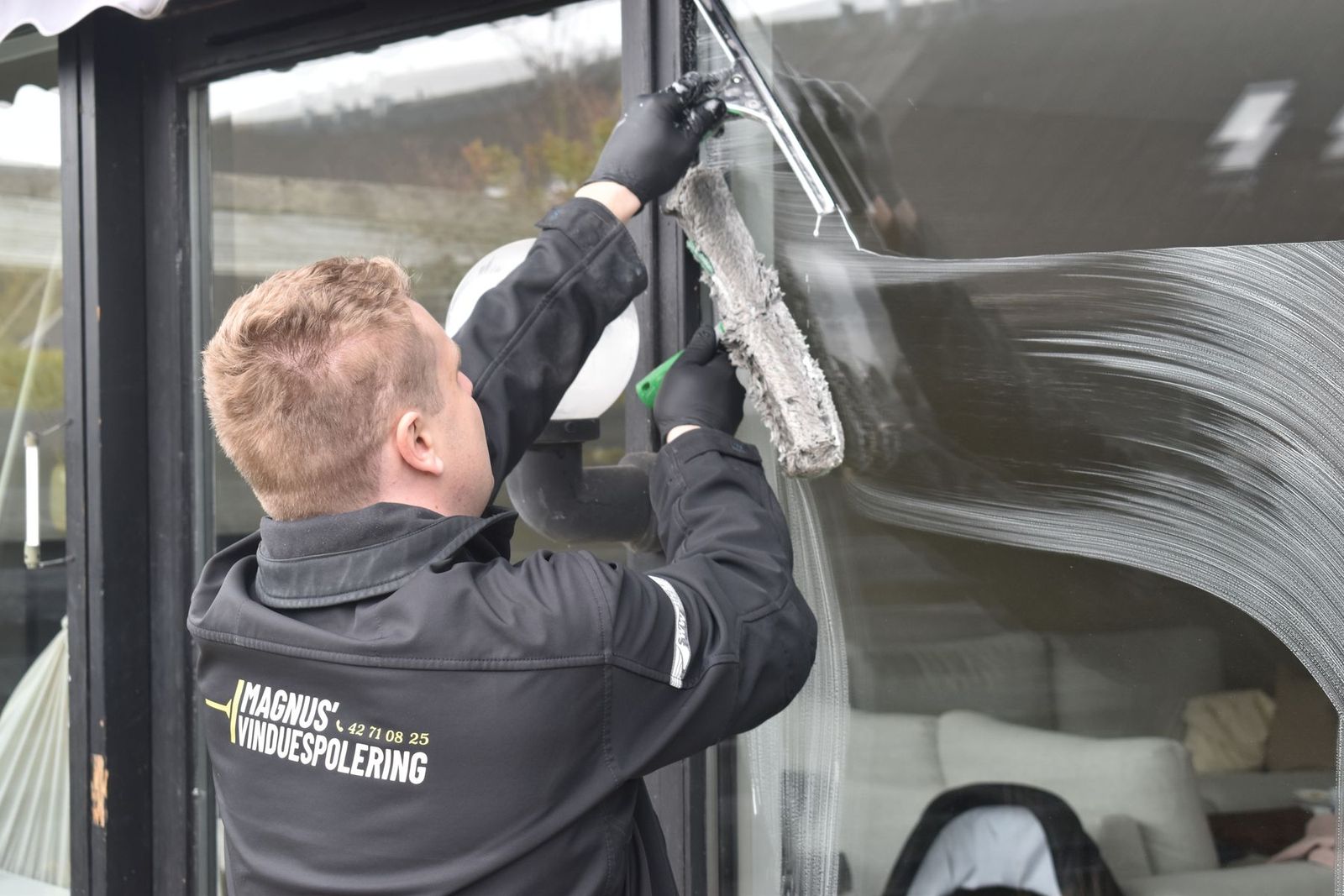 Große Fensterscheibe wird von einem Reinigungsbetrieb gewaschen